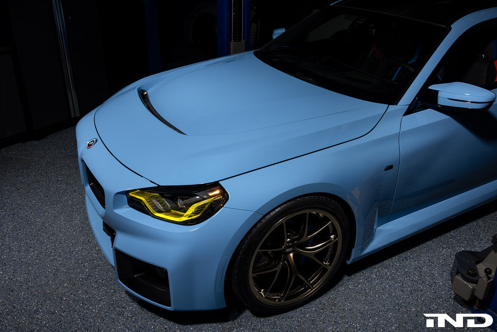 Alpha N G87 M2 carbon vented hood with front vent insert installed on a vehicle, showcasing its sleek exterior design.
