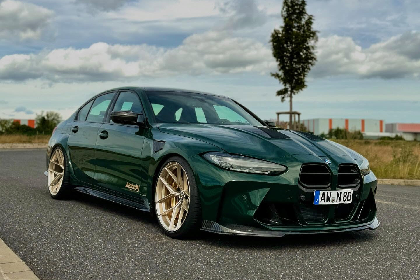 Alpha N G8X M3 M4 carbon front spoiler installed on vehicle, showcasing sleek exterior design and aerodynamic enhancements.