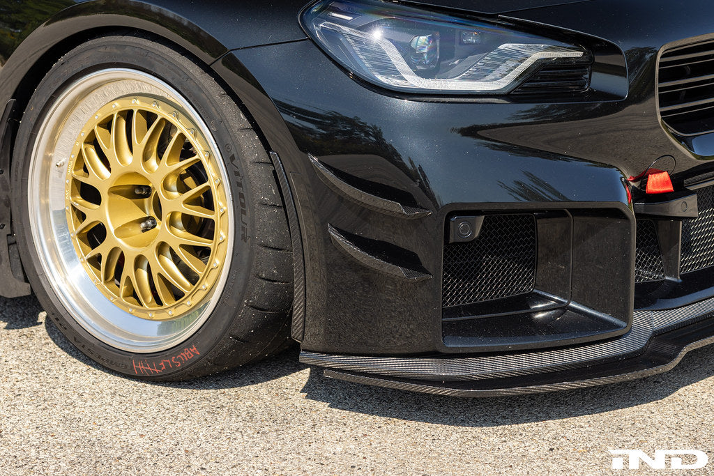 Alpha N G87 M2 carbon bumper canard set installed on vehicle, showcasing aerodynamic exterior enhancements.