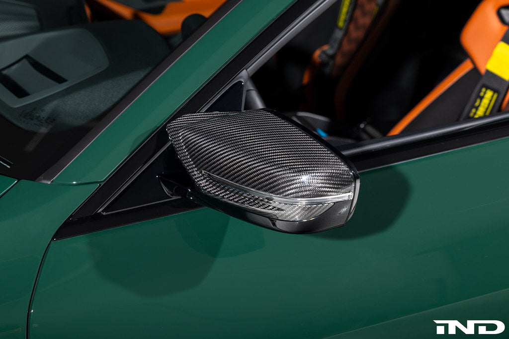 Alpha N G8X M2 M3 M4 carbon mirror cap set installed on exterior of vehicle, showcasing sleek black carbon fiber finish.