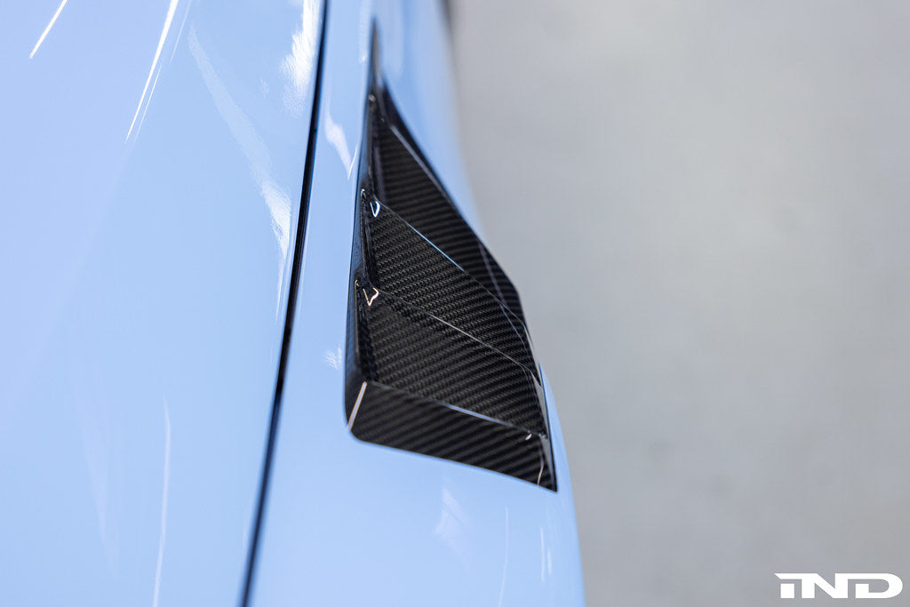 Alpha N G87 M2 carbon vented front fender set with blades installed on a vehicle, showcasing sleek exterior design and venting details.